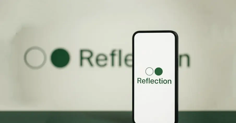 لوگوی Reflection AI روی صفحه یک گوشی هوشمند، با لوگوی بزرگ و محوشده Reflection در پس‌زمینه.